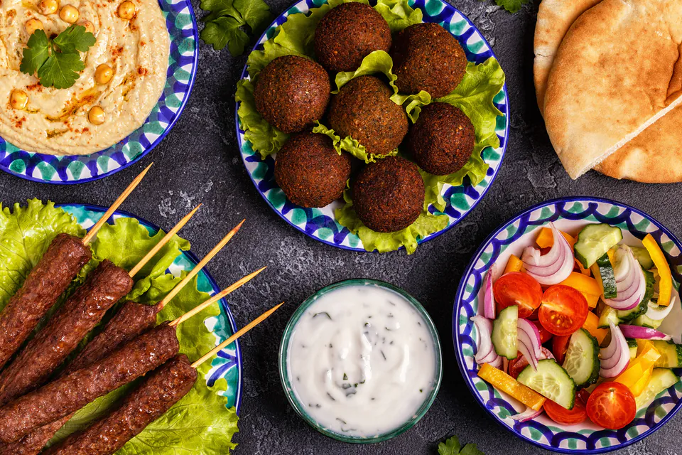 Middle Eastern mezze spread with falafel, hummus, kebabs and fresh salad on decorative plates