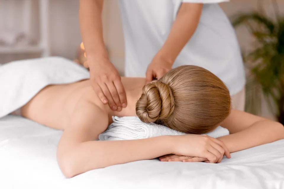 Therapeutic massage being performed in a spa treatment room with white linens