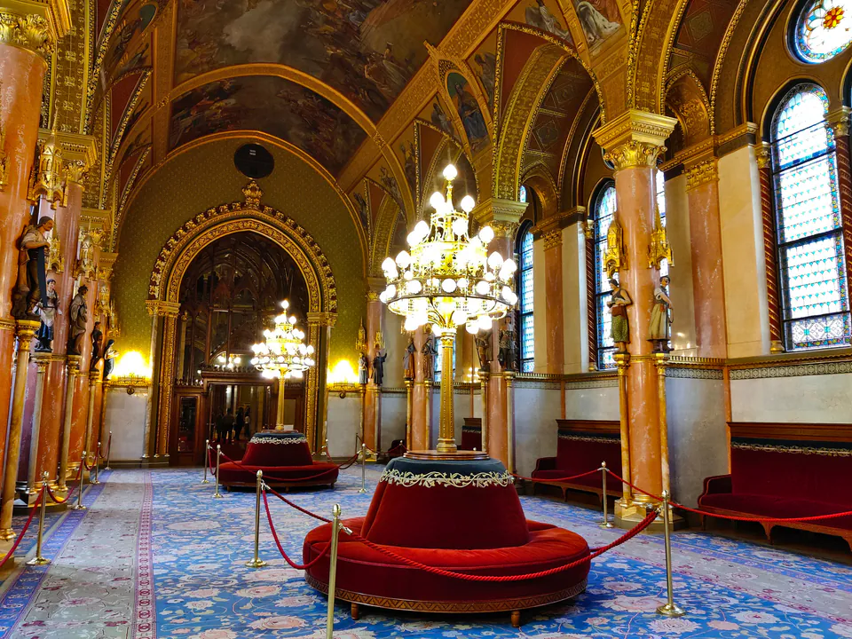 Ornate lobby interior with vaulted golden ceilings, chandeliers, and circular red velvet seating