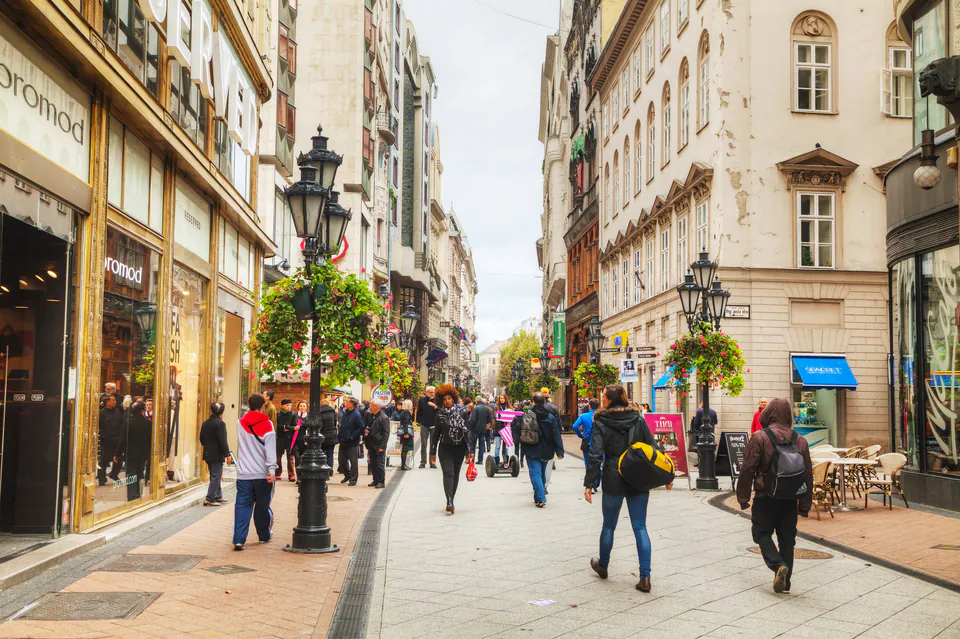 Busy pedestrian shopping street in Budapest with historic buildings and decorative lampposts