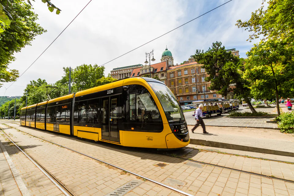 Modern low-floor Budapest tram at busy Grand Boulevard stop with passengers boarding
