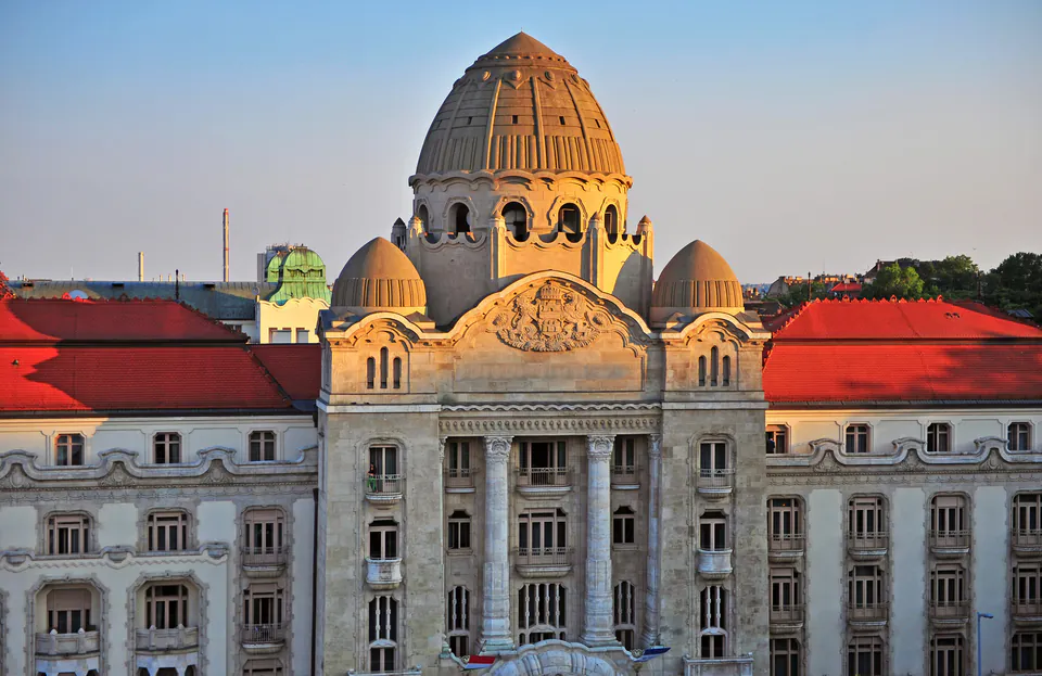 Ornate domed rooftop and facade of historic Gellért Bath building at sunset