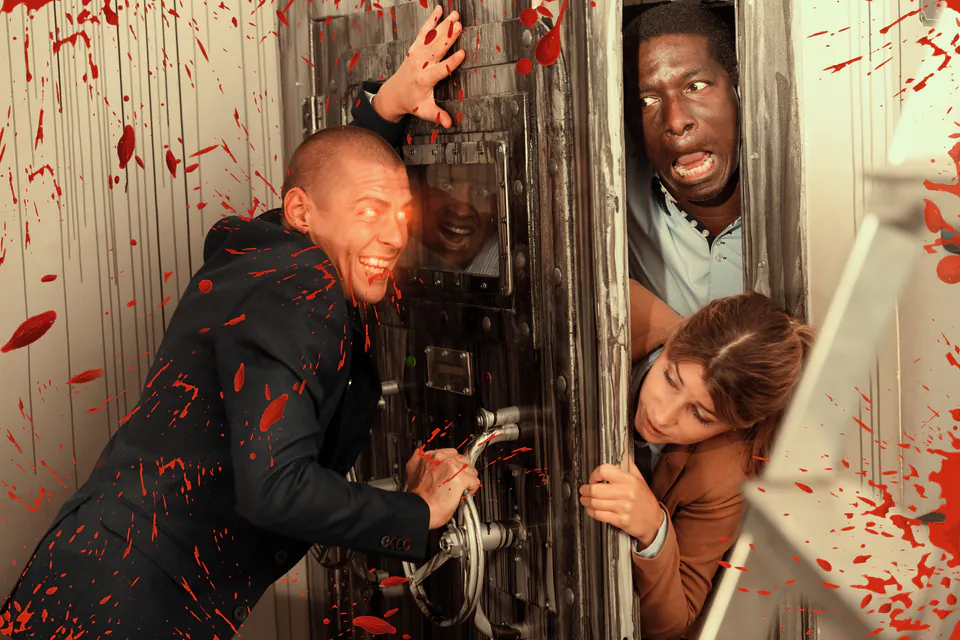 Group of players reacting dramatically in a horror-themed escape room with red splatter effects