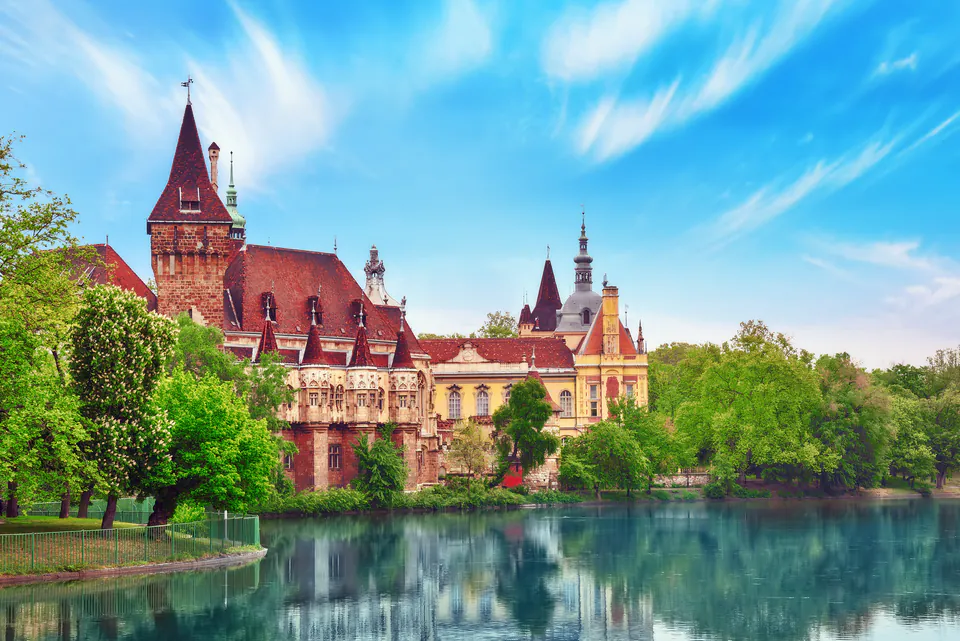 Fairy-tale Vajdahunyad Castle reflecting in the calm waters of City Park lake on a sunny day