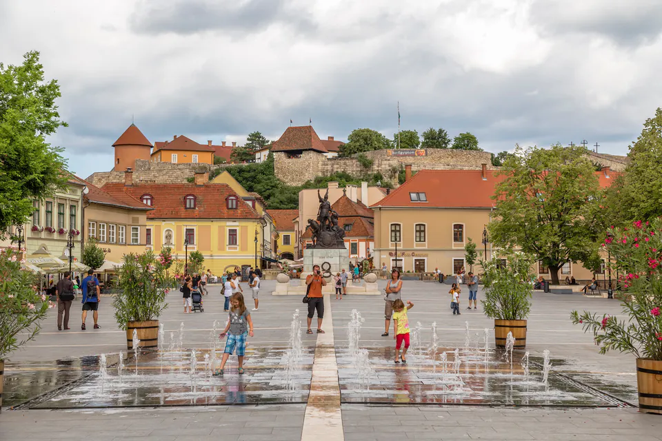 Historic Dobó Square with fountains, baroque buildings and castle hill in background