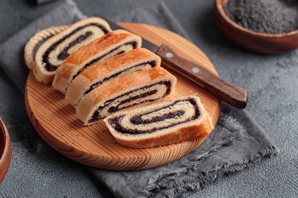 Sliced bejgli roll showing spiral layers of poppy seed filling in traditional Hungarian Christmas pastry