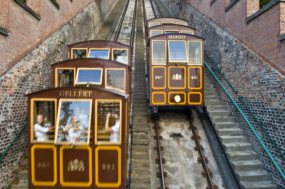 Historic funicular railway cars passing each other on steep Castle Hill tracks between brick walls