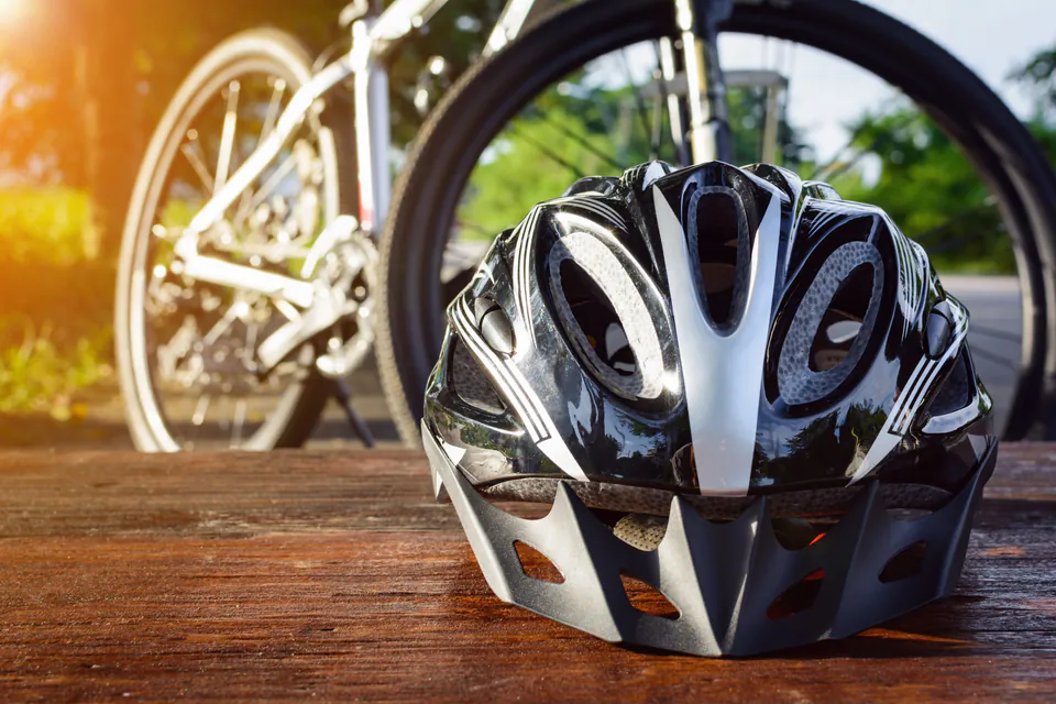 Close-up of bicycle helmet with bike wheel blurred in background