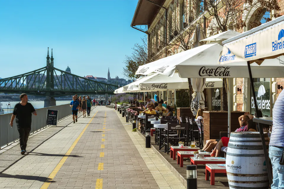 Riverside promenade with casual outdoor seating and Liberty Bridge view in Budapest