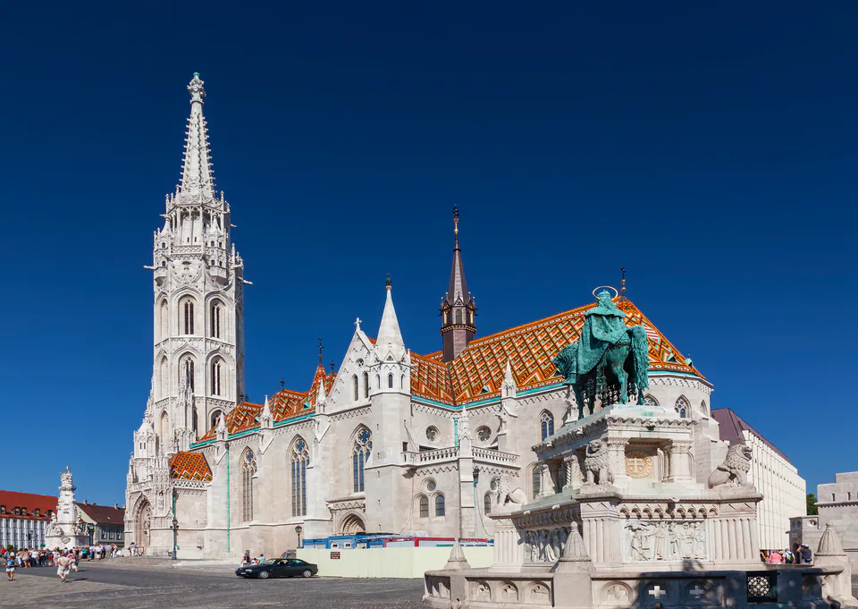 Colorful tiled roof of Matthias Church with Gothic spires against blue sky