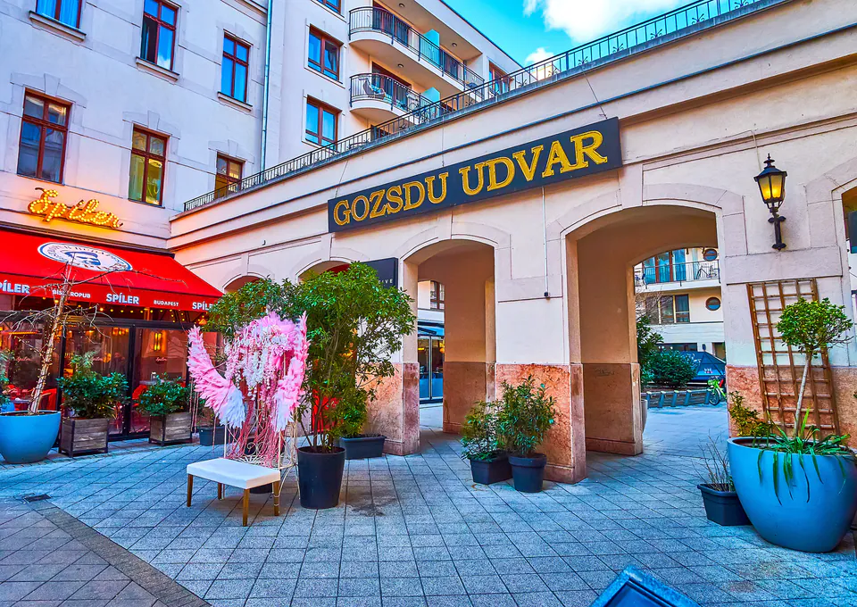 Entrance archway to Gozsdu Udvar with decorative plants and cafe seating in Budapest's Jewish Quarter