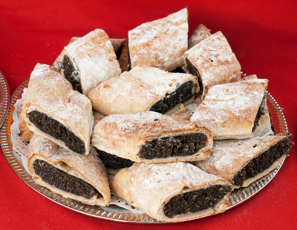 Traditional Hungarian poppy seed strudel slices dusted with powdered sugar on silver platter