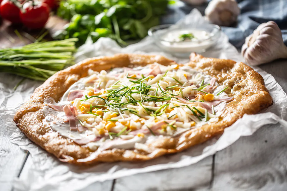 Traditional Hungarian lángos topped with sour cream and cheese