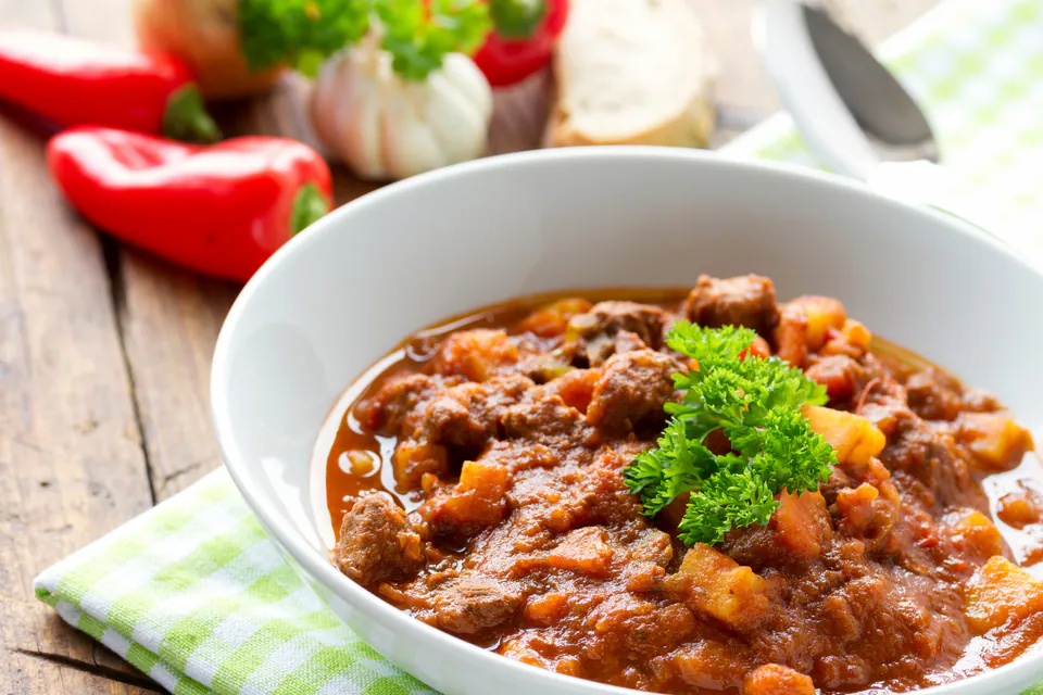 Steaming bowl of Hungarian goulash with tender meat and vegetables in rich paprika broth
