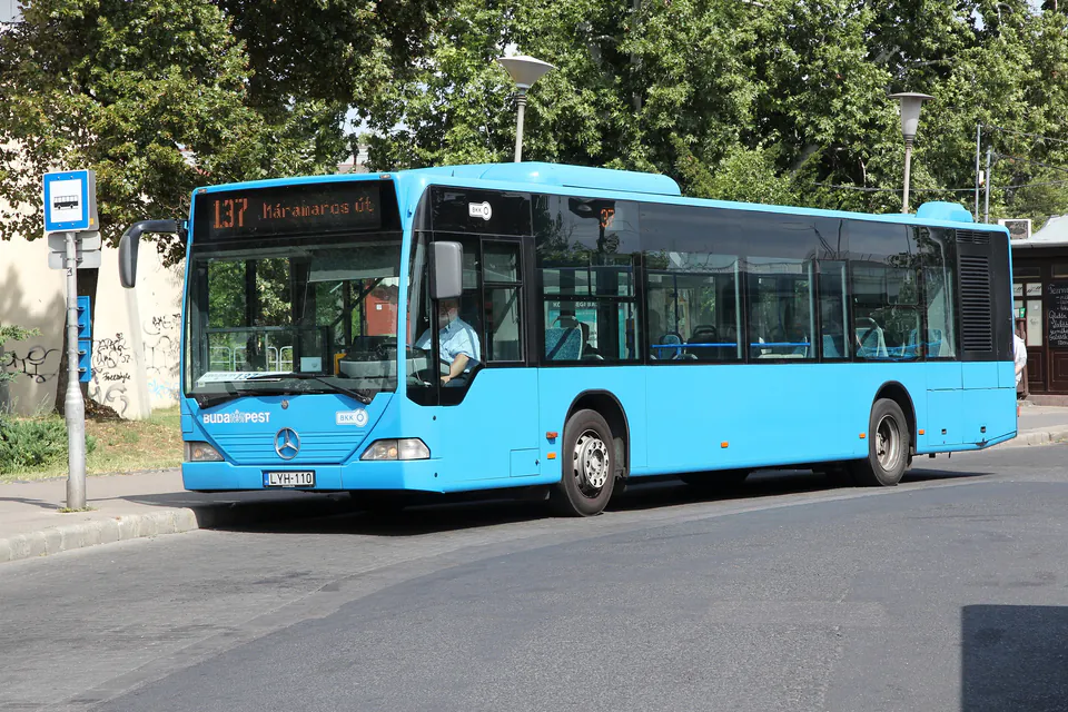 Passengers boarding blue Budapest bus through front door while validating tickets