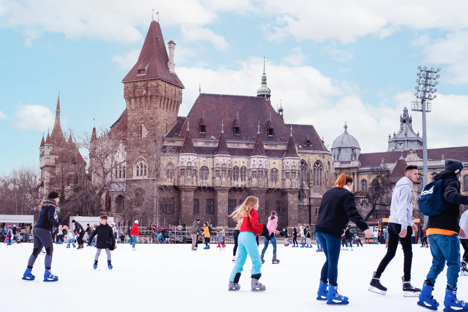 Families ice skating at City Park winter ice rink with castle backdrop