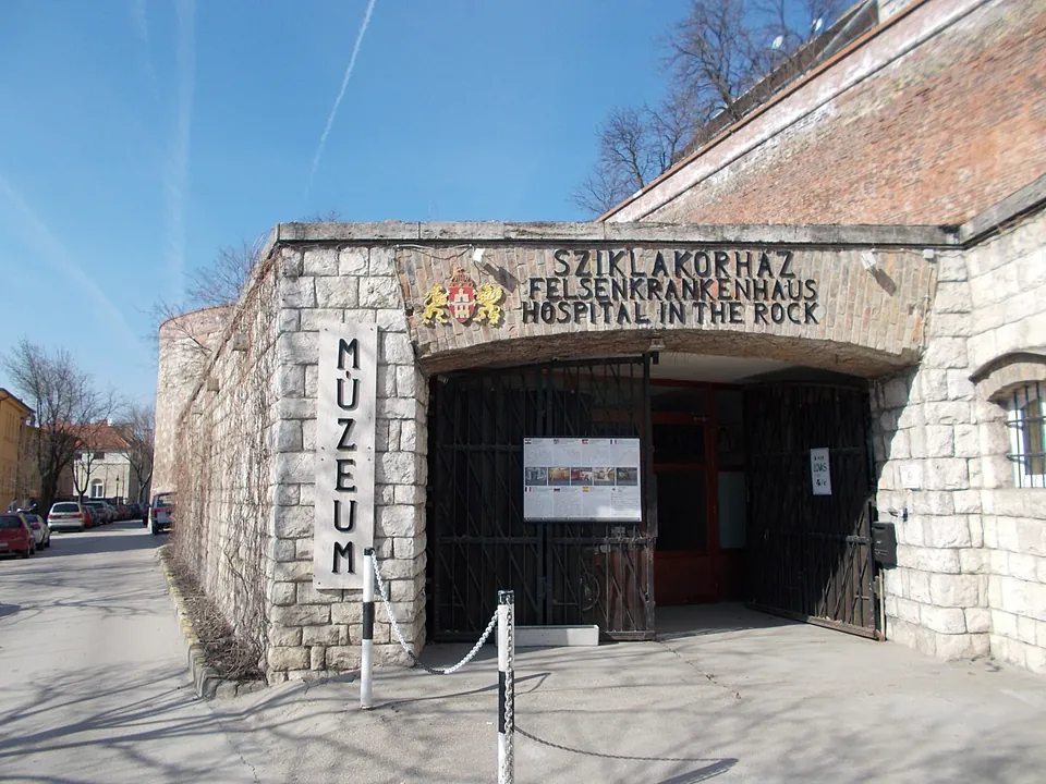 Stone entrance to Hospital in the Rock museum with multilingual signage and museum marker