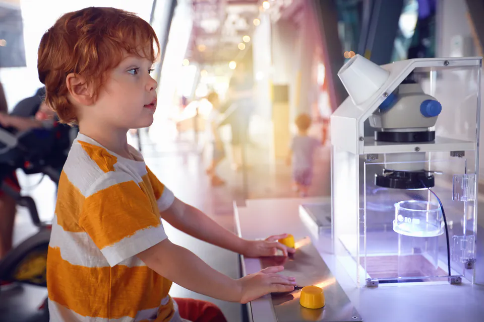 Young visitor interacting with hands-on science exhibit at museum display