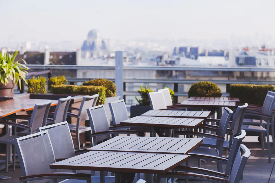 Outdoor rooftop terrace with tables and chairs overlooking city skyline