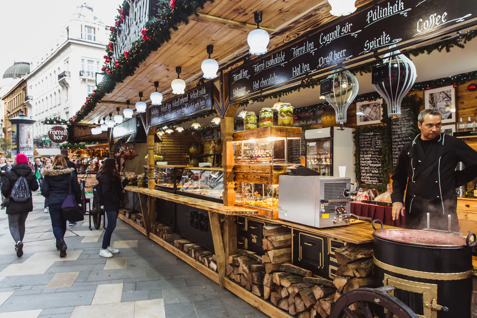 Festive wooden market stall with glowing lights selling food and drinks in Budapest