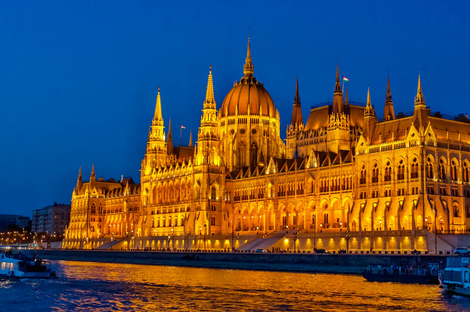 Hungarian Parliament Building illuminated at night with golden lights reflecting on the Danube River